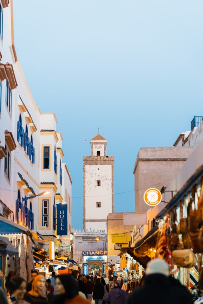 a group of people walking down a street next to tall buildings